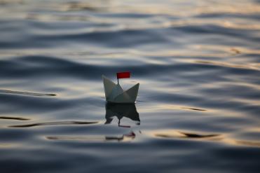 Papierboot mit roter Flagge auf dem Wasser