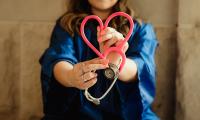 Frau hält Stethoskop und bildet Herz