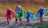 Kinder in verschiedenfarbigen Regenmänteln