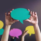 Hände halten Sprechblasen aus Papier hoch