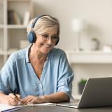 Frau mit Kopfhörern, an einem Laptop sitzend