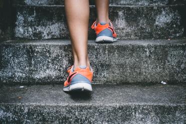 Mensch in Sportschuhen geht eine Treppe hoch